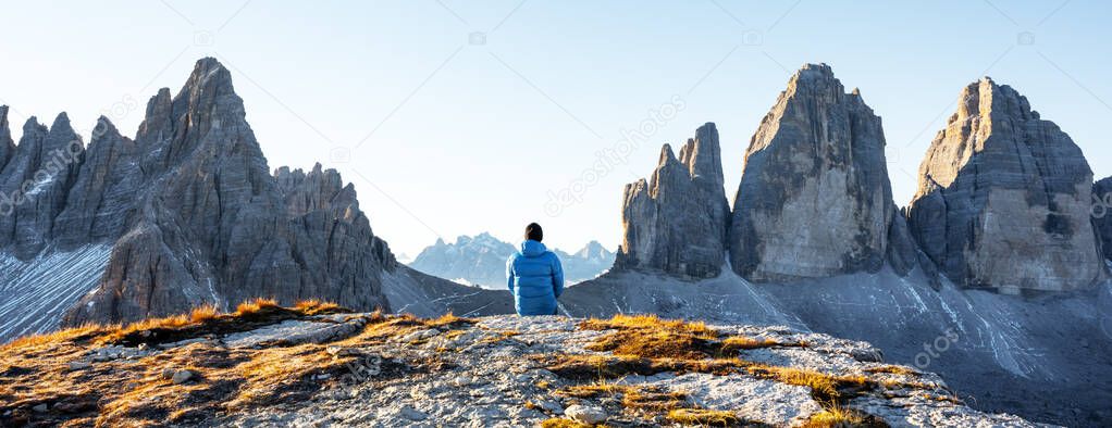 Tourist in blue jacket at Three Peaks of Lavaredo track on autumn season