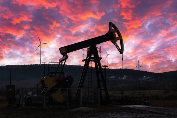 Bomba de aceite y turbinas eólicas contra el increíble cielo púrpura atardecer — Foto de Stock