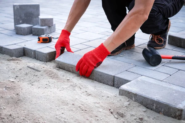 The master in yellow gloves lays paving stones — Stock Photo, Image