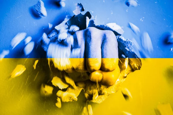 A fist punches through a concrete wall with the colors of the Ukrainian flag