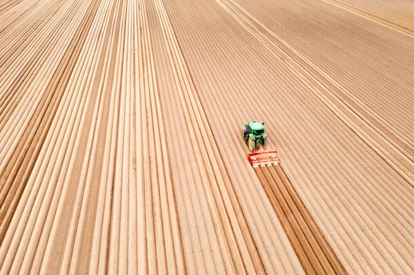 Ensam traktor på jordbruksmark med rader av plöjd jord — Stockfoto