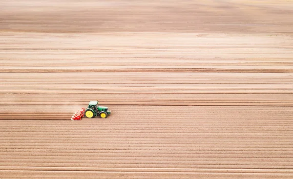 Tractor solitario en el campo agrícola con hileras de tierra arada —  Fotos de Stock