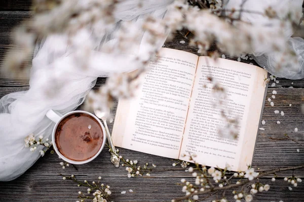 Tasse mit heißem Schokoladenkakao, altem Buch und Frühlingsblumen — Stockfoto