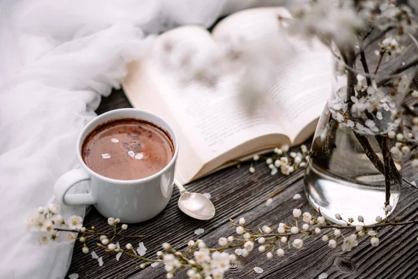 Copo de cacau de chocolate quente, livro velho e flores de cereja primavera — Fotografia de Stock