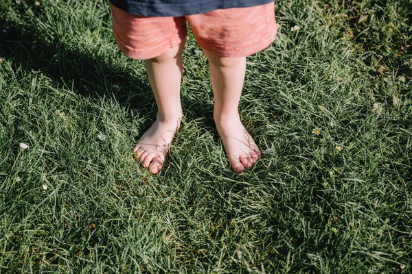 Крупный план мальчика, стоящего босиком на зеленой траве — стоковое фото