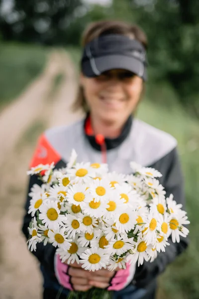 목초지에서 자전거타는 소녀의 모습을 야생화 꽃다발 — 스톡 사진