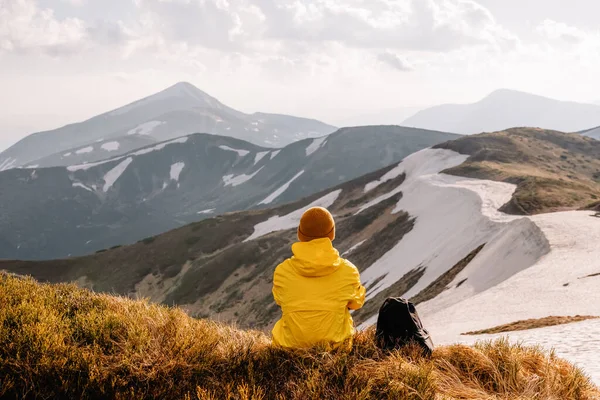 Turysta Siedzi Skraju Szczytu Góry Słoneczne Góry Śniegiem Tle Fotografia — Zdjęcie stockowe