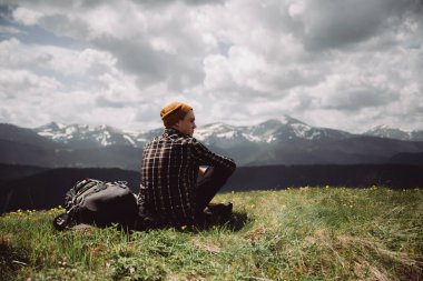 Bir turist bir dağ zirvesinin kenarında oturur. Arka planda sisli dağlar. Peyzaj fotoğrafçılığı