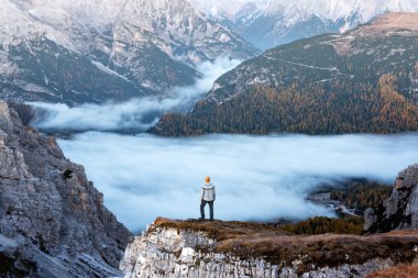 Bir turist Dolomitler dağlarındaki bir uçurumun kenarında sisin üzerinde duruyor. Auronzo Rifugio, Tre Cime di Lavaredo Ulusal Parkı, Dolomitler, Trentino Alto Adige, İtalya
