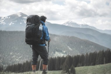 Bahar dağlarında yürüyüş yapan sırt çantalı bir turist. Arka planda karlı dağlar var. Peyzaj fotoğrafçılığı