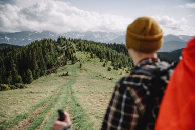 A tourist with backpack on the mountains road. Green spring mountains on the background. Landscape photography