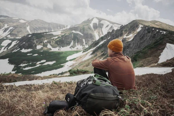 一个旅游者坐在山顶的边缘上 后面是多雾的山 景观摄影 — 图库照片