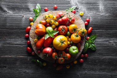 Different varieties kind of red, yellow, green and black tomato mix on wooden table. Fresh assorted colorful summer tomatoes background, close up. Food photography