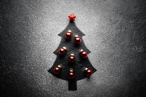 黒を背景に人工雪から作られた上に赤いクリスマスボールと星を飾るクリスマスツリー 冬休みのコンセプト — ストック写真
