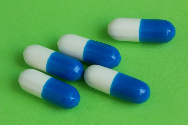 Blue and white capsule on a green background — Stock Photo, Image