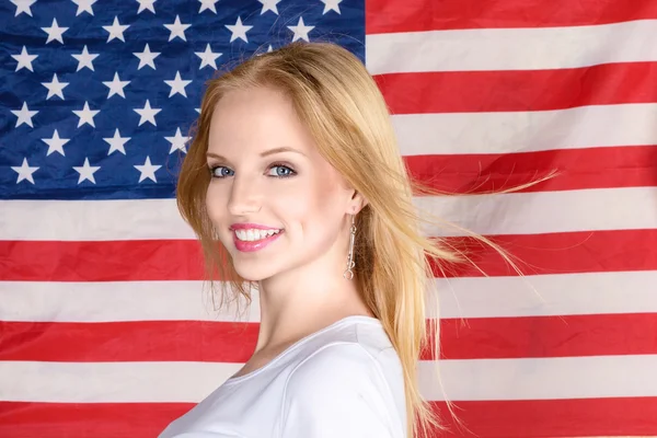 Jovem loira posando contra bandeira americana — Fotografia de Stock