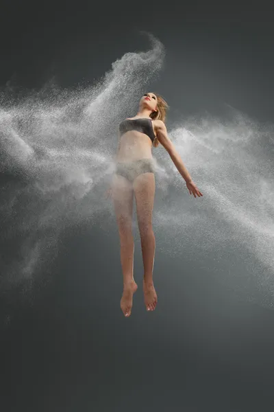 Танцівниця стрибає в хмару з білого порошку — стокове фото