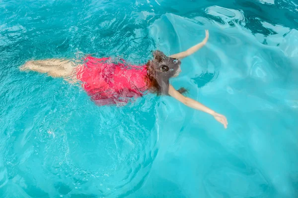 Uma jovem nadando debaixo d 'água na piscina — Fotografia de Stock