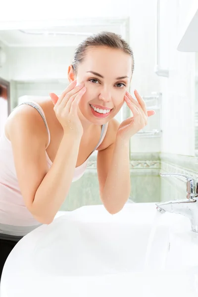 Giovane donna che si lava il viso con acqua pulita — Foto Stock