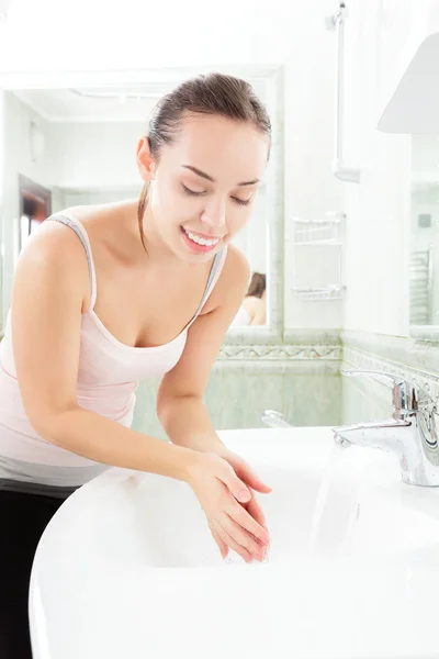 Jeune femme se lave le visage avec de l'eau propre — Photo