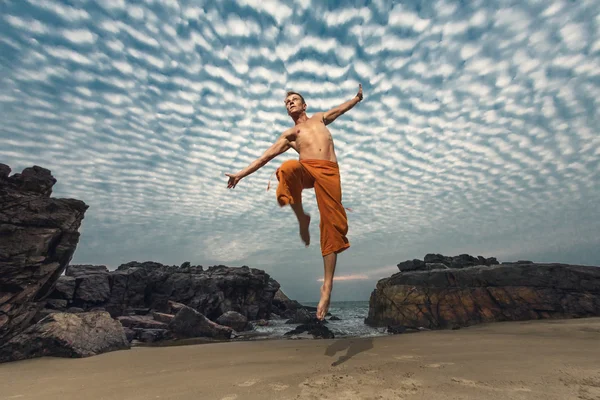 Jovem salto em altura na praia — Fotografia de Stock