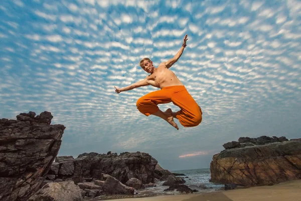 Young man high jumping on beach — Stock Photo, Image