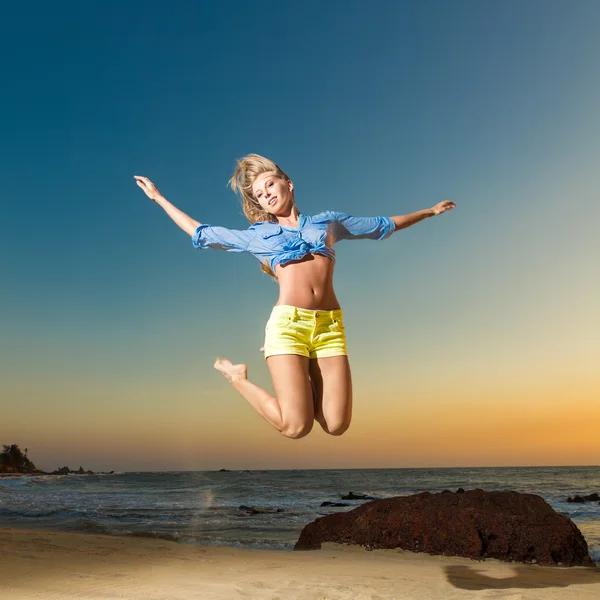 Gelukkig jonge vrouw springen op strand — Stockfoto