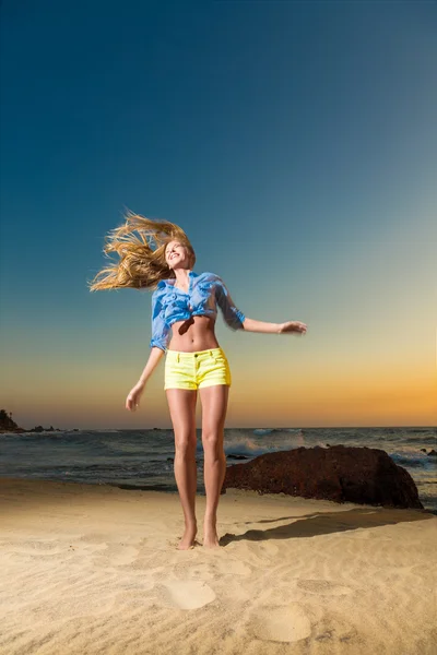 Happy young woman jumping on beach — Stock Photo, Image