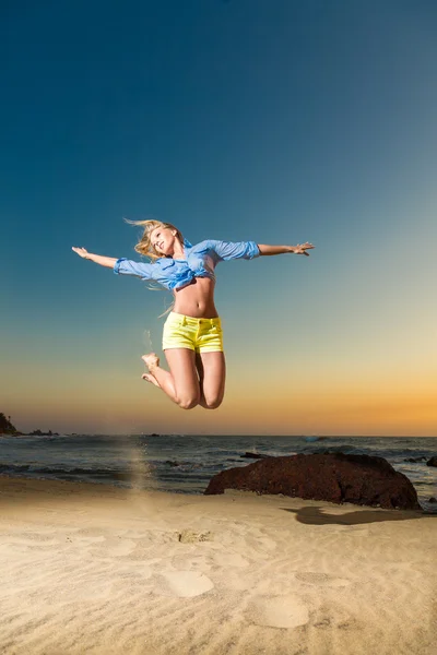 Happy young woman jumping on beach — Stock Photo, Image