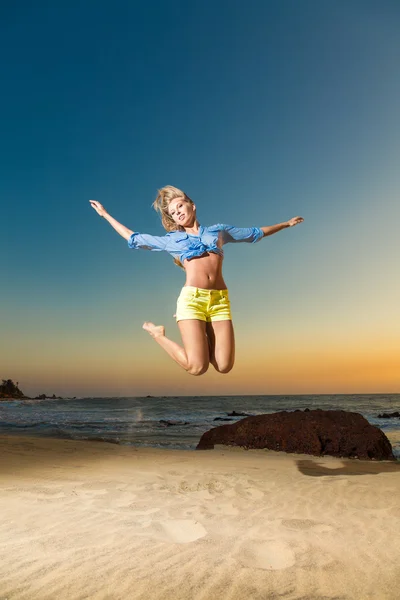 Happy young woman jumping on beach — Stock Photo, Image