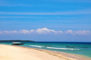 Agung Dağı aktif yanardağ Nusa Penida, Bali Adası, Endonezya 'da bulutlarla kaplı. Beyaz kumsalda jukung adında geleneksel balıkçı tekneleri. Köpüklü dalgalar kıyıya yayıldı..