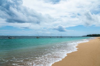 Okyanusta yüzen balıkçı tekneleri. Açık sularda seyir eden ahşap tekne. Yelkenli manzarası. Köpüklü yüksek dalgalar kıyıya yayıldı. Tropik bir manzara. Endonezya 'daki Bali Adası. Yaz tatili.