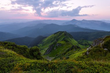 Güzel gün doğumuyla dağ manzarası, bulutlu gökyüzü ve pembe renkli ufuk. Bahar güneşli bir sabah. Duvar kağıdı arka planı. Deniz Piyadeleri, Karpatlar, Ukrayna, Avrupa.