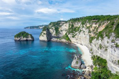 Landscape of sunny day with turquoise ocean, blue sky and mountains. View of Diamond beach, Nusa Penida, Bali island, Indonesia. Wallpaper background. Natural scenery. Romantic relax place.