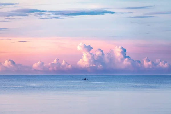 Tropical ocean landscape. Pink sky with cloud. Sunrise. Resort Bali island, Indonesia. Summer vacation. Fishing boats floating on the ocean. Wooden boat sailing in open waters.