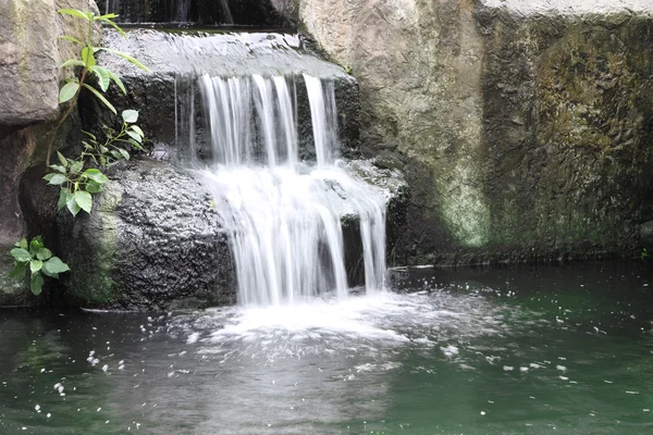 Pequena cachoeira de dois níveis no jardim tropical público . — Fotografia de Stock