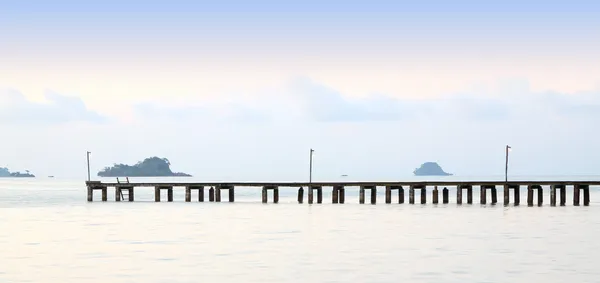 Long wooden pier port on morning beach. — Stock Photo, Image