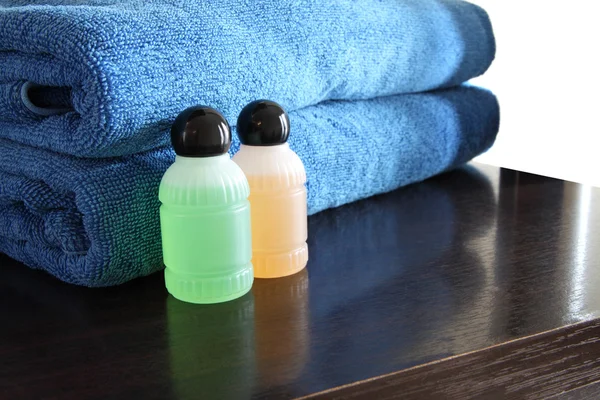 スパのボトルと木製のテーブルの上の青いタオル. — ストック写真