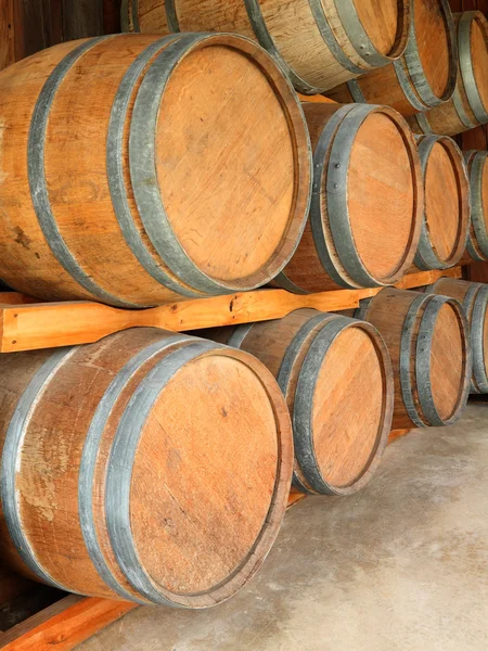 Stack of round wooden wine barrels in cellar shelf. — Stock Photo, Image