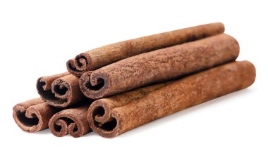 Beyaz arka planda bir yığın tarçın çubuğu var. İzole edilmiş