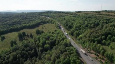 Güneşli bir yaz sabahında çam ağaçlarıyla yeşil ağaçlar arasındaki hava manzaralı yol. Sibirya, Rusya 'da doğa manzarası. Kozalaklı bir ormandan geçen bir yol, İHA 'dan havadan çekilen bir görüntü..