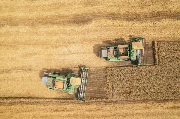 Cosecha combinada: vista aérea de la máquina agrícola recogiendo trigo maduro dorado en camión. — Foto de Stock