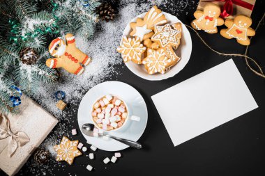 Noel ve Yeni Yıl dekorasyonu. Koyu arkaplandaki kürk ağacı dallarının en üst görüntüsü. Marşmelovlu, zencefilli ve çikolatalı fincanlar..