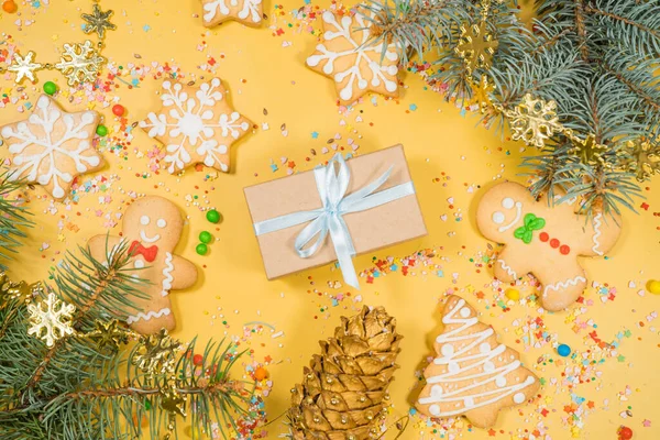 Boże Narodzenie piernika ciasteczka w różnych kształtach i prezent na żółtej powierzchni. Płaskie ułożenie, widok z góry. Zdjęcia Stockowe bez tantiem
