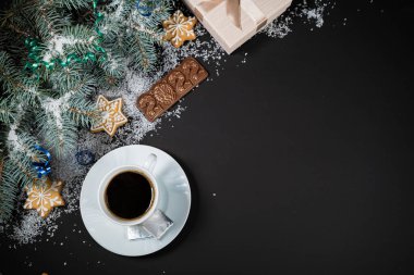 Noel ve Yeni Yıl dekorasyonu. Koyu arkaplandaki kürk ağacı dallarının en üst görüntüsü. Marşmelovlu, zencefilli ve çikolatalı fincanlar..