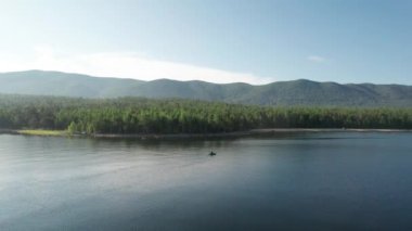 Baykal Gölü 'nün destansı sinematik manzarası. Bir dağ ormanı gölünde çam ağaçlarıyla birlikte turkuaz su. Mavi göl ve yeşil ormanların havadan görünüşü. Dağ ormanları arasındaki göle bak..