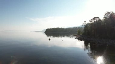 Baykal Gölü 'nün destansı sinematik manzarası. Bir dağ ormanı gölünde çam ağaçlarıyla birlikte turkuaz su. Mavi göl ve yeşil ormanların havadan görünüşü. Dağ ormanları arasındaki göle bak..