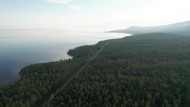 Epický filmový letecký výhled na jezero Bajkal po ránu. Tyrkysová voda v horském jezeře s borovicemi. Letecký pohled na modré jezero a zelené lesy. Pohled na jezero mezi horskými lesy. — Stock video