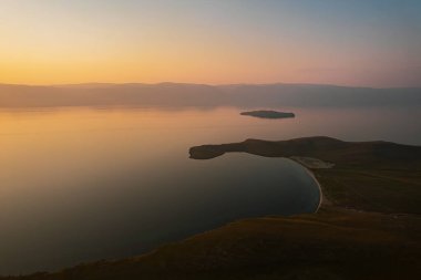 Olkhon Island at sunrise, the largest island in Lake Baikal in eastern Siberia. Shamanka Rock on Baikal lake near Khuzhir at Olkhon island in Siberia, Russia. clipart