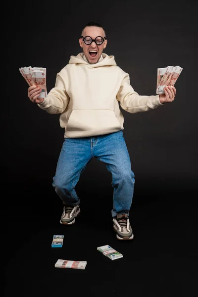 若い幸せなビジネスマンは黒の背景に隔離されたお金のスタックで踊る. — ストック写真